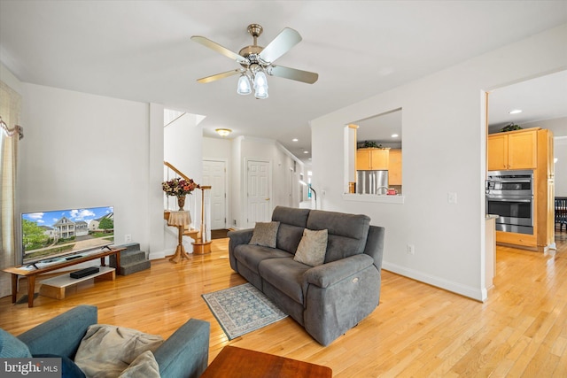 living area featuring stairs, light wood-style floors, baseboards, ceiling fan, and recessed lighting