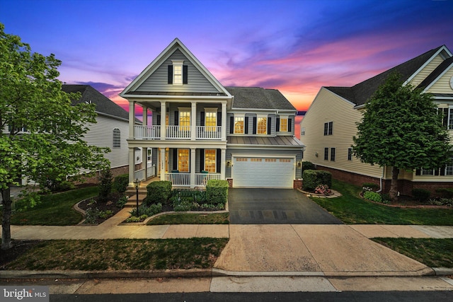 view of front of house with an attached garage, a porch, concrete driveway, a balcony, and a yard