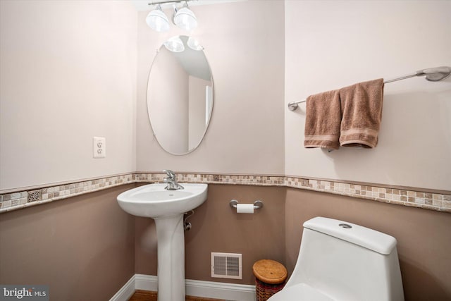 bathroom featuring a sink, toilet, and visible vents