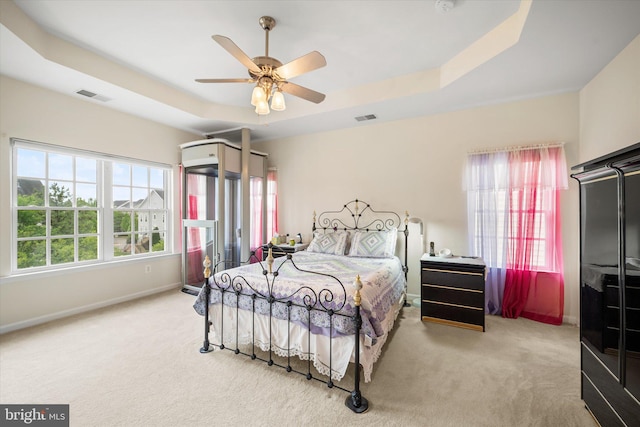 bedroom featuring carpet, a tray ceiling, and visible vents