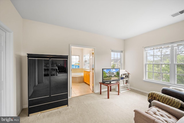 living area with baseboards, light colored carpet, a wealth of natural light, and visible vents