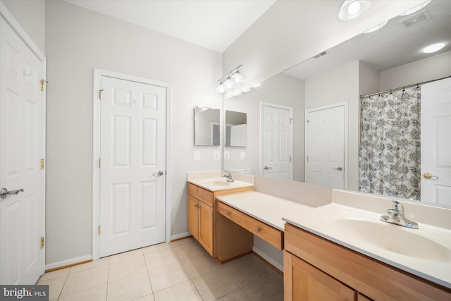 bathroom featuring double vanity, a sink, baseboards, and tile patterned floors