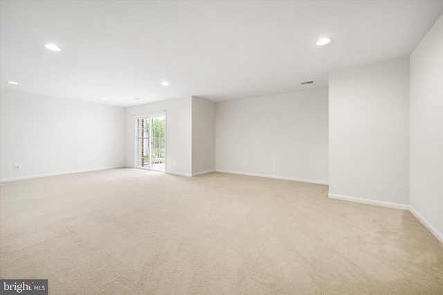 spare room featuring light colored carpet, recessed lighting, and baseboards