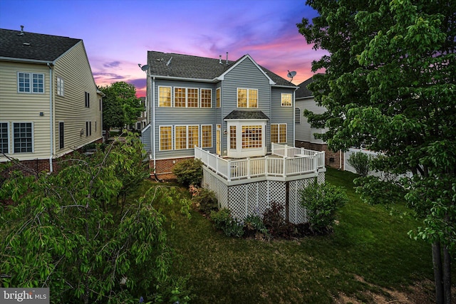 rear view of house featuring a lawn, a shingled roof, and a deck