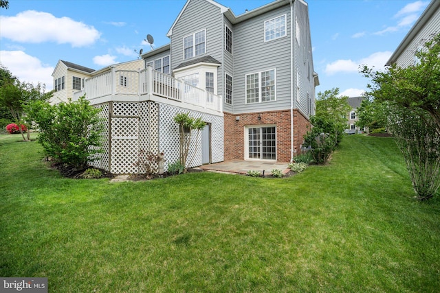 back of property featuring a yard, a patio area, and brick siding