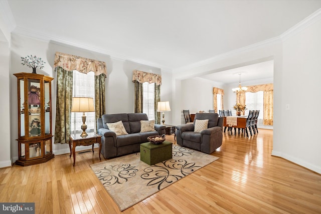 living area featuring crown molding, a notable chandelier, a healthy amount of sunlight, and hardwood / wood-style flooring