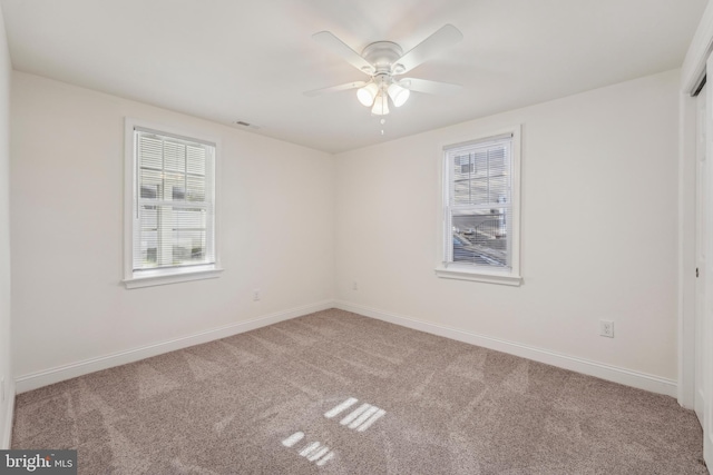 carpeted empty room with baseboards, plenty of natural light, and a ceiling fan
