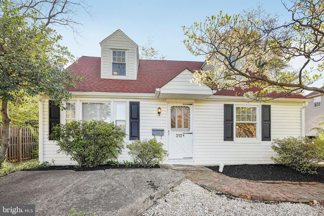 cape cod-style house featuring fence