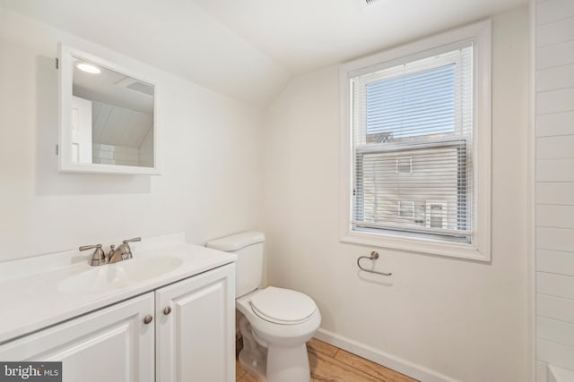 bathroom featuring vanity, baseboards, lofted ceiling, and toilet