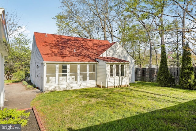 back of property featuring roof with shingles, fence, and a yard