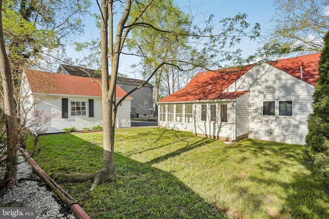 rear view of house with a sunroom and a yard