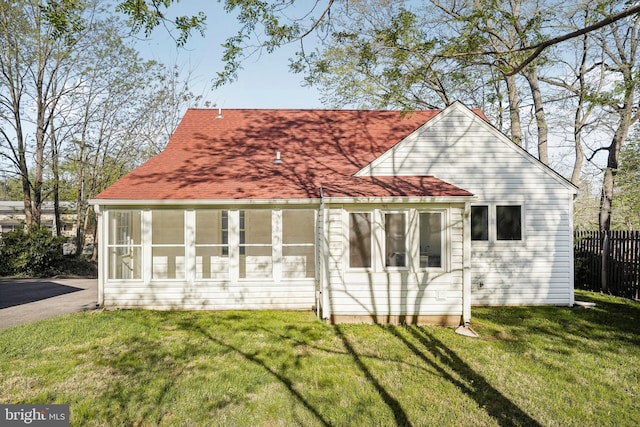 back of property featuring a lawn, fence, and a shingled roof