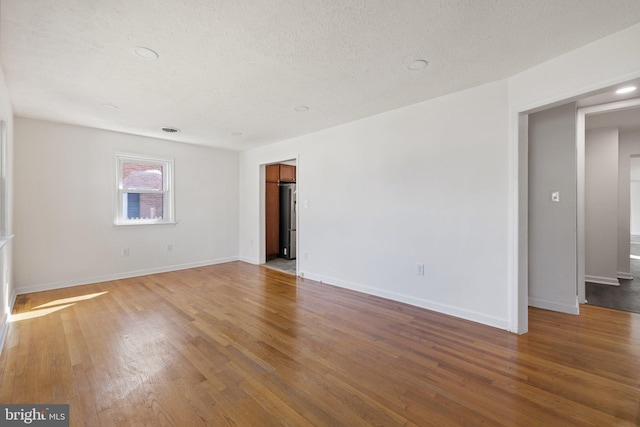 empty room featuring baseboards, wood finished floors, a textured ceiling, and recessed lighting