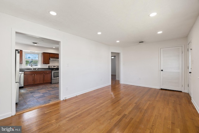 interior space featuring baseboards, wood finished floors, a sink, and recessed lighting