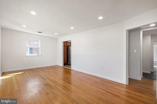 empty room with baseboards, recessed lighting, and light wood-style flooring