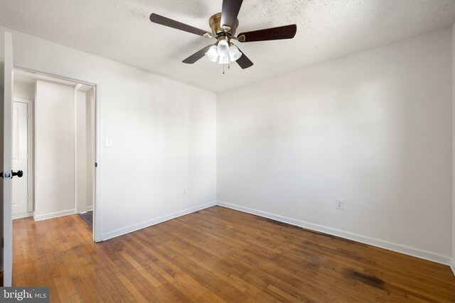 spare room with baseboards, a ceiling fan, wood finished floors, and a textured ceiling