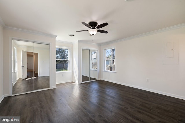 unfurnished bedroom featuring dark wood-type flooring, two closets, crown molding, and baseboards