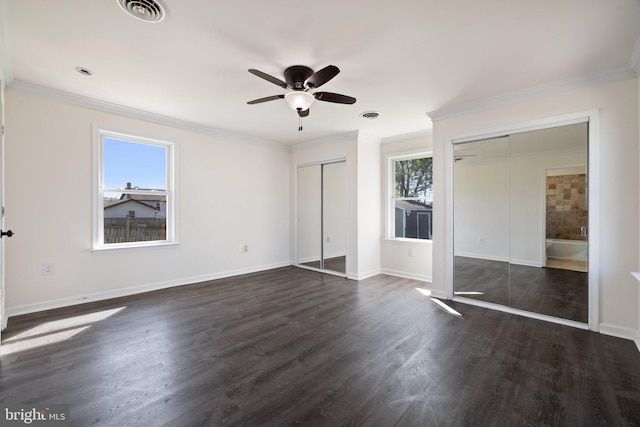 unfurnished bedroom with dark wood-style floors, baseboards, multiple closets, and visible vents