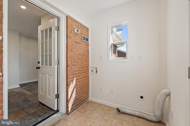 interior space with hookup for an electric dryer, baseboards, washer hookup, brick wall, and laundry area