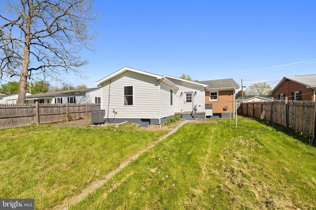 back of house featuring entry steps, a lawn, and a fenced backyard