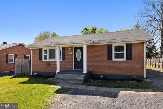view of front of house with brick siding, a front lawn, and fence