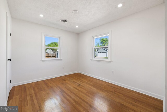 spare room with wood-type flooring, baseboards, and a healthy amount of sunlight