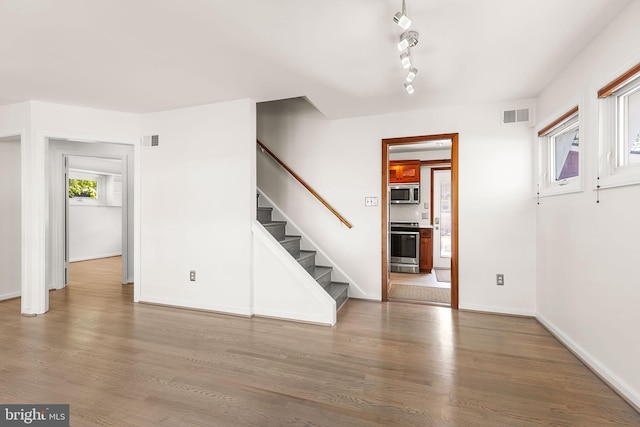 interior space with baseboards, visible vents, wood finished floors, and stairway