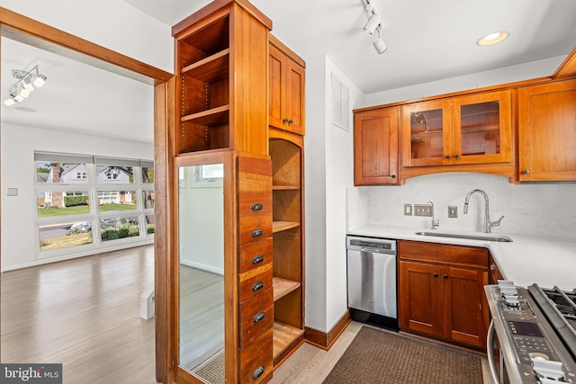 kitchen featuring rail lighting, a sink, light countertops, light wood finished floors, and stainless steel appliances