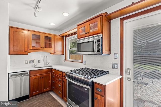 kitchen featuring a sink, appliances with stainless steel finishes, brown cabinets, and light countertops