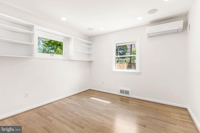 spare room with baseboards, visible vents, a wall unit AC, and plenty of natural light