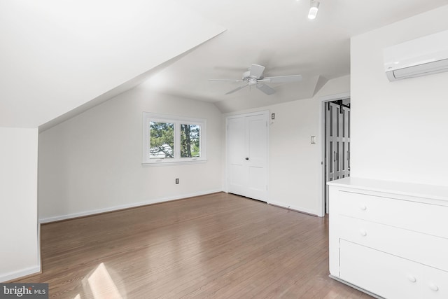 additional living space featuring ceiling fan, a wall mounted AC, light wood finished floors, and lofted ceiling