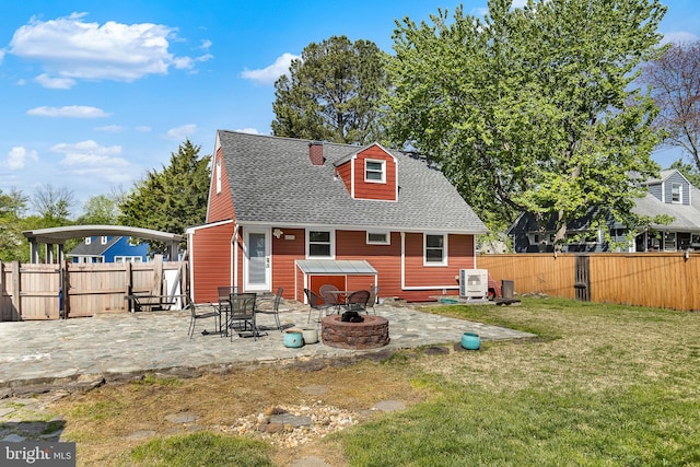 back of property featuring roof with shingles, a fenced backyard, a yard, a patio, and a fire pit