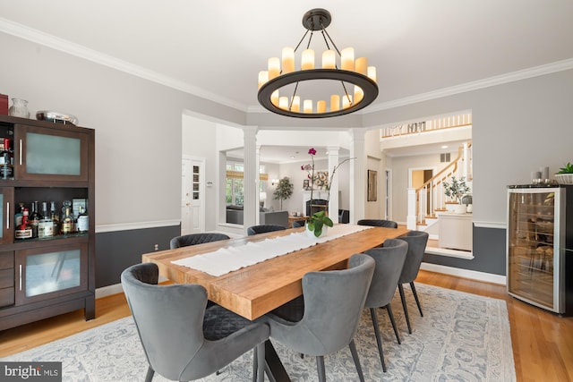 dining space with decorative columns, beverage cooler, stairs, a chandelier, and crown molding