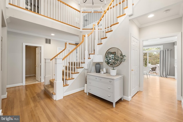 stairs with wood finished floors, crown molding, baseboards, a high ceiling, and recessed lighting