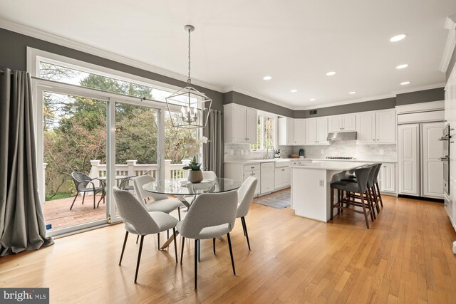 dining space featuring crown molding, light wood-type flooring, a chandelier, and recessed lighting