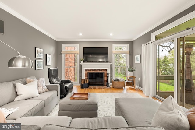 living area with light wood-style flooring, ornamental molding, recessed lighting, baseboards, and a brick fireplace