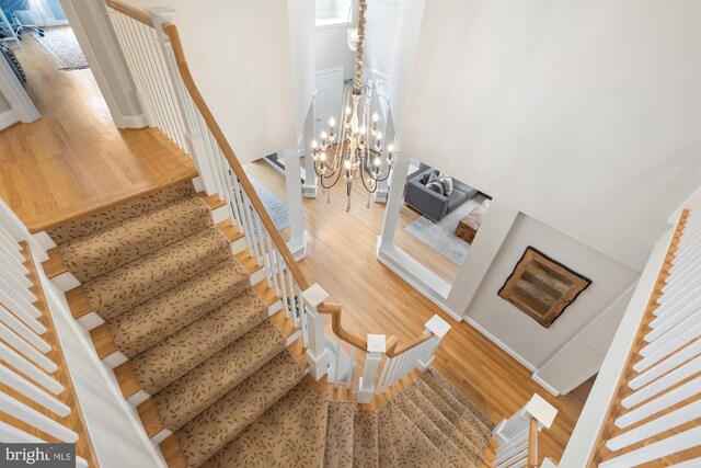 staircase with wood finished floors and a chandelier
