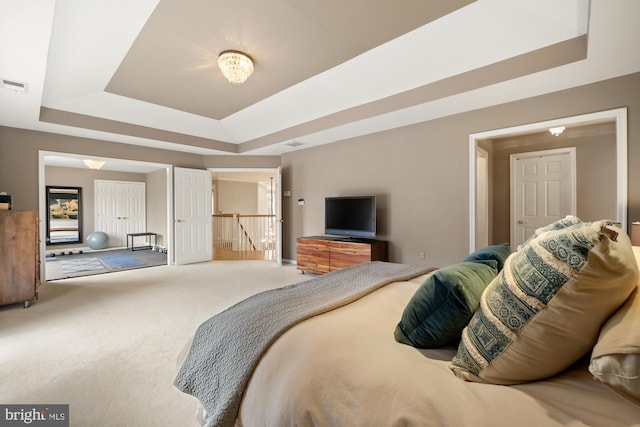 carpeted bedroom featuring a tray ceiling and baseboards