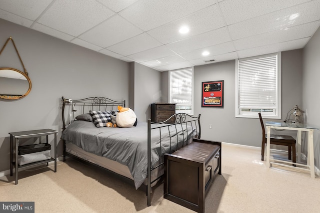 bedroom featuring light carpet, a drop ceiling, and baseboards