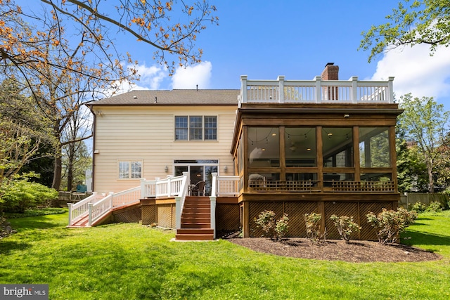 rear view of house with stairs, a sunroom, a deck, a yard, and a chimney