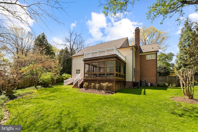 rear view of house with a sunroom, a chimney, central AC, and a balcony