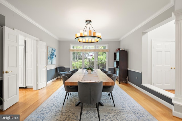 dining space with light wood finished floors, a chandelier, ornamental molding, and baseboards