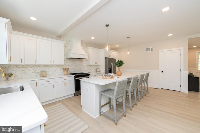 kitchen with a sink, stainless steel appliances, visible vents, backsplash, and premium range hood