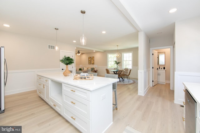 kitchen with white cabinetry, visible vents, wainscoting, and light wood-style flooring