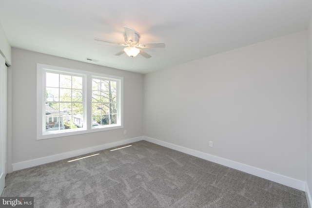 unfurnished room with dark carpet, ceiling fan, visible vents, and baseboards