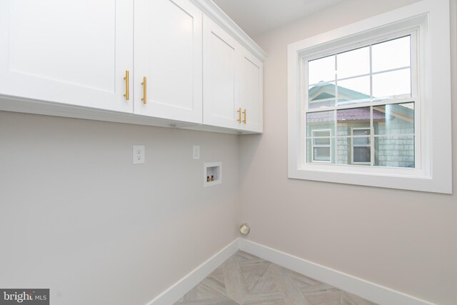 clothes washing area featuring hookup for a washing machine, cabinet space, and baseboards