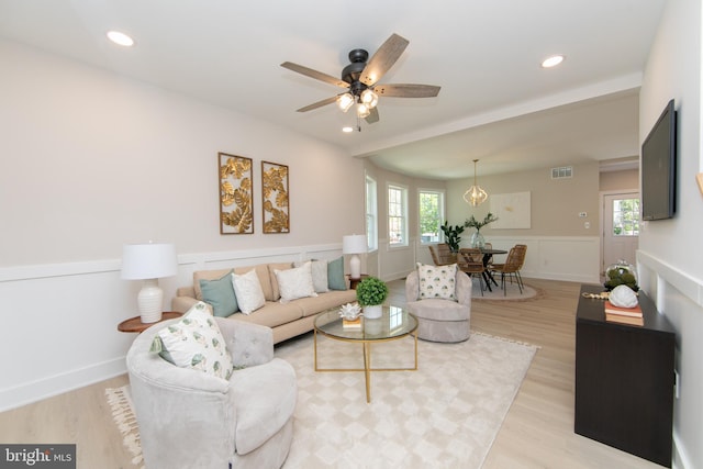living area featuring visible vents, ceiling fan, light wood finished floors, and plenty of natural light