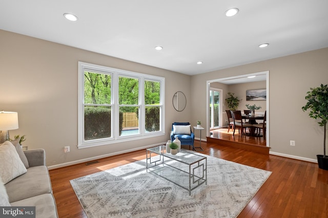 living area with recessed lighting, visible vents, wood finished floors, and baseboards