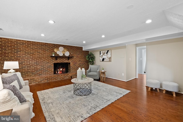 living room with recessed lighting, brick wall, a textured ceiling, and a fireplace