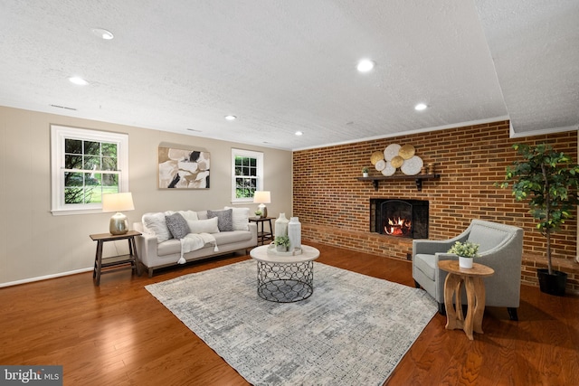 living room featuring a textured ceiling, brick wall, plenty of natural light, and a brick fireplace